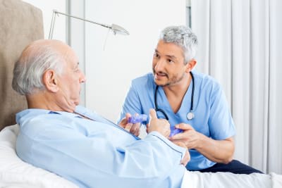 male caregiver explaining prescription to senior man in bedroom at nursing home