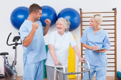 smiling caregivers with senior woman in the fitness studio